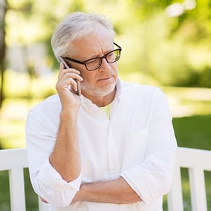 technology, senior people, and communication concept - old man in glasses calling on smartphone at summer park
