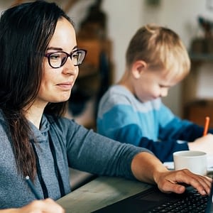 woman using a laptop working from home while next to her child